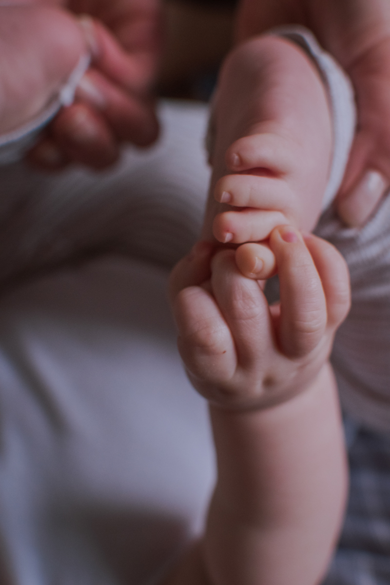 Close-up of a baby hand gently grasping an adult finger, highlighting the tenderness and connection between them.