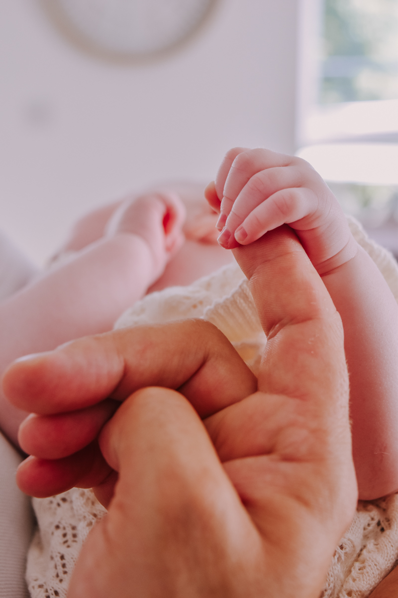 A close-up image capturing a parent gently holding a baby's hand, emphasizing tenderness and connection.
